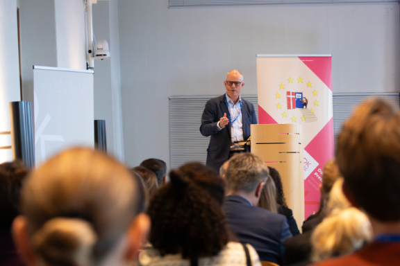 Paul Mollerup talar framför en publik.